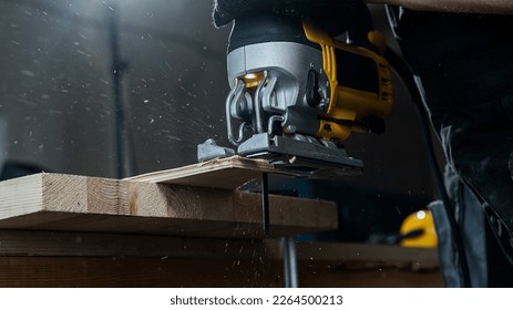 Close-up of a man cutting a wooden plank with an electric jigsaw in a workshop. - Powered by Shutterstock