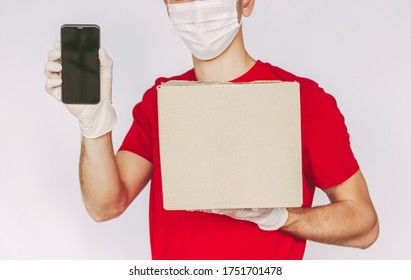 Closeup Man Delivery Service Worker In Medical Face Mask, Protective Glove Hold Smart Phone, Cardboard Box In Hand, Empty Copy Space. Delivery Guy Carry Parcel Box, Mobile Phone, Isolated Background