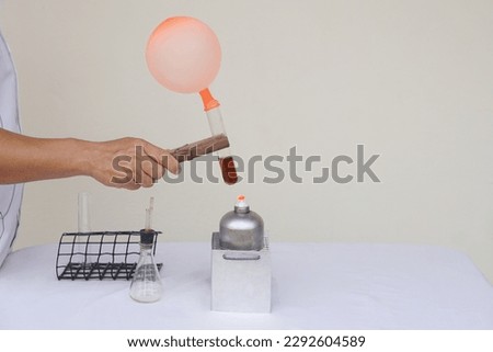 Closeup man is doing science exeriment , holds balloon on test tube is burned from lantern.The expanding of air pressure, reaction of chemical substance. Concept, Science activity.    