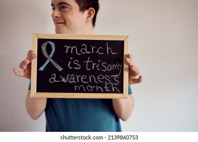 Close-up of man with down syndrome holding trisomy 21 awareness sign.