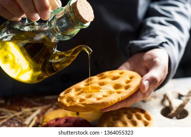 Closeup Of A Man Dressing With Olive Oil A Variety Of Different Focaccia, With Pumpkin, Carrot And Beet, On A Rustic Wooden Table