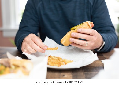 Closeup Of A Man Eating A Chicago Style Hotdog With Everything And French Fries At Home - Takeout Food Delivery