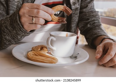 Close-up Of A Man Eating A Typical Sweet Spanish Breakfast And Churros With Chocolate