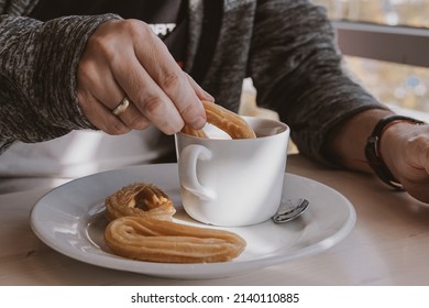 Close-up Of A Man Eating A Typical Sweet Spanish Breakfast And Churros With Chocolate