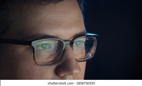 Closeup Of Man Eyes In Eyeglasses In Front Of The Computer, Concentrated Look. Young Man Sitting Working Alone At Night