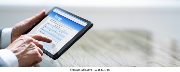 Close-up Of A Man Filling Online Survey Form On Digital Tablet