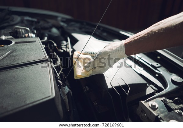 Close-up. The man is fixing the car. Checks engine\
oil level