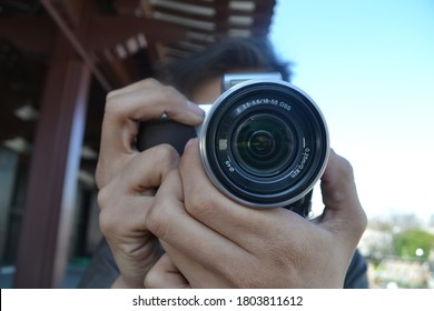 Closeup of man focusing camera lens. Photographer hands are on the lens and button ready to take a picture.