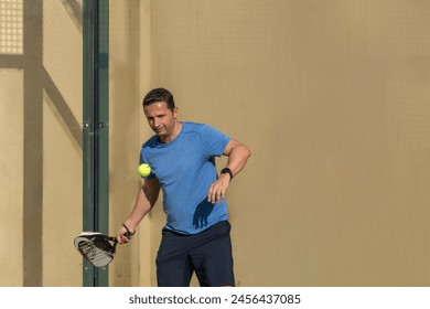 Close-up of a man focusing on his forehand swing during a padel tennis game, illustrating concentration and skill. - Powered by Shutterstock