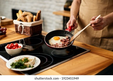 Close-up Of Man Frying Eggs And Bacon For Breakfast In The Kitchen,