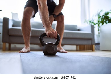 Closeup of man grabing kettlebell during home workout exercises