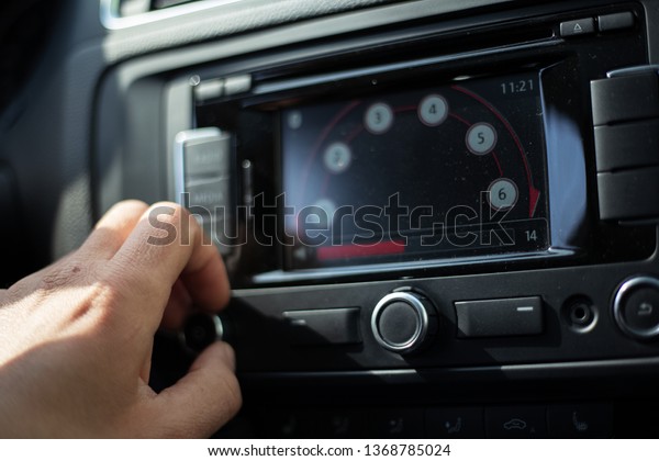 Close-up of man hand adjusts the volume control\
of car audio system.