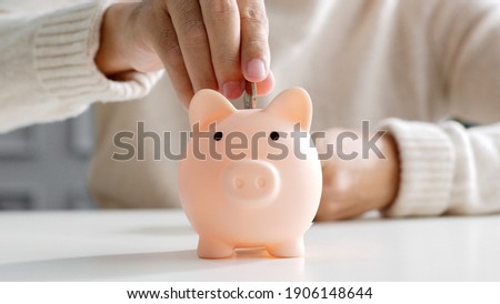 Closeup man hand put coin money to piggy bank, saving and deposit money concept