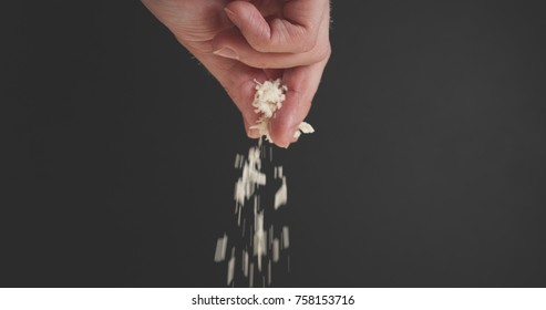 Closeup Of Man Hand Sprinkle Grated Aged Parmesan Over Dark Background