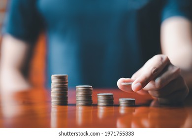 Closeup man hands. Businessman holding coin to place on stack of coins placed on the table. Accounting, Financial investment, saving money for future growth concept. - Shutterstock ID 1971755333