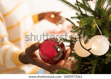 Closeup man hands decorating Christmas tree wit red toys at home