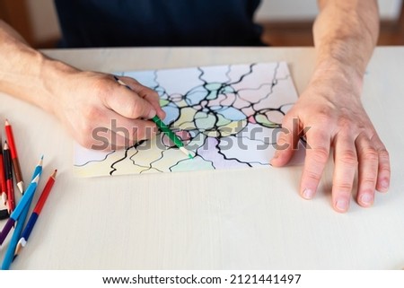 Close-up of man hands drawing neurographic art.  Mental health, adult fine motor skill, creativity, psychology. Abstract neurographic drawing with marker, colored pencils. Art therapy. Selective focus