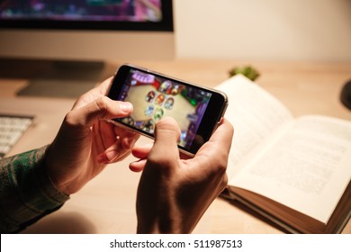 Closeup of man hands playing videogames on cell phone in the evening