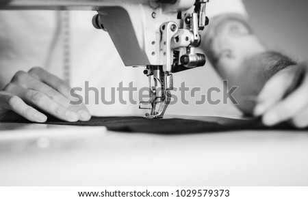 Close-up man hands sewing fabric on sewing machine