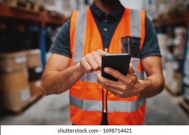 Closeup of man hands using mobile phone while in warehouse in uniform - Powered by Shutterstock