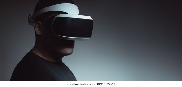 Close-up of a man in his thirties wearing virtual reality glasses on a dark background. The concept of artificial intelligence, hacking, fraud. - Shutterstock ID 1921476047