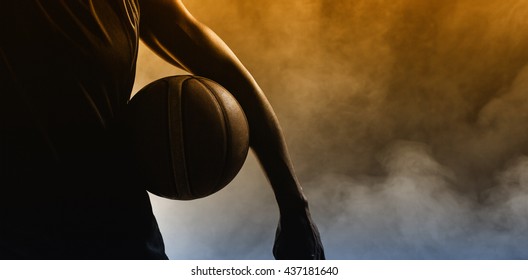 Closeup of a man holding a basketball with dark light - Powered by Shutterstock