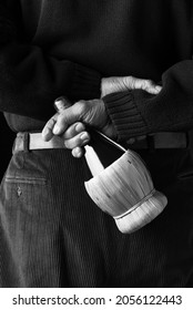 Closeup Of A Man Holding A Chianti Wine Bottle Behind His Back.