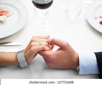 Closeup Of A Man Holding His Girlfriend's Hand At The Restaurant