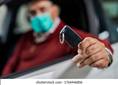 Close-up Of A Man Holding Keys Of His New Car While Wearing Face Mask During Coronavirus Epidemic.