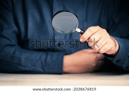 Closeup man holding a magnifying glass, searching tool, analysis,  and scrutiny concept