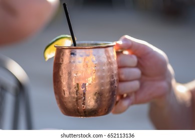 Closeup Of A Man Holding A Moscow Mule Mixed Drink In A Copper Mug Outside On A Sunny Summer Day - Soft Focus