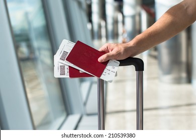 Closeup of man holding passports and boarding pass at airport - Shutterstock ID 210539380