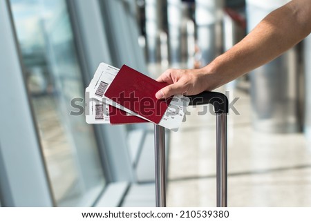 Closeup of man holding passports and boarding pass at airport