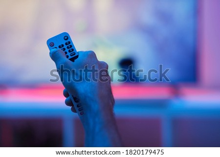 Close-up of man holding remote control during watching TV at home