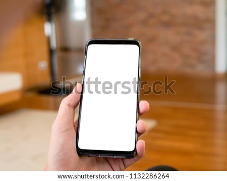 closeup man holding smartphone in hand, relax sitting and using smart phone with blank copy space isolate white screen for graphic application or advertising in cafe or co-working space. 