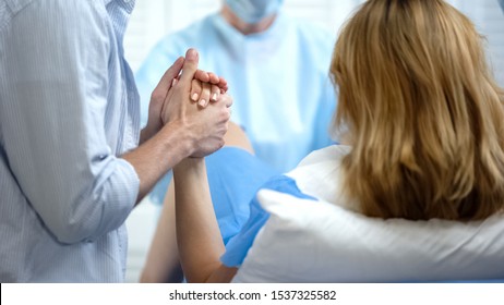 Close-up of man holding wife hand for support during pushing to give childbirth