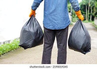 Closeup man holds black plastic bag that contains garbage inside. Concept : Waste management. Environment problems. Daily chores. Throw away rubbish.                             - Shutterstock ID 2190019245