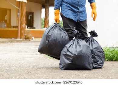 Closeup man holds black plastic bag that contains garbage inside. Concept , Waste management. Environment problems. Daily chores. Throw away rubbish .                        