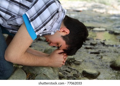 Close-up Of Man Kneeling And Praying By A Creek