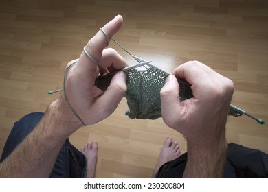 Closeup Of A Man Knitting A Green Scarf At Home