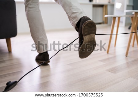 Close-up Of A Man Legs Stumbling With An Electrical Cord At Home