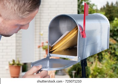 Close-up Of A Man Looking Inside The Silver Mailbox