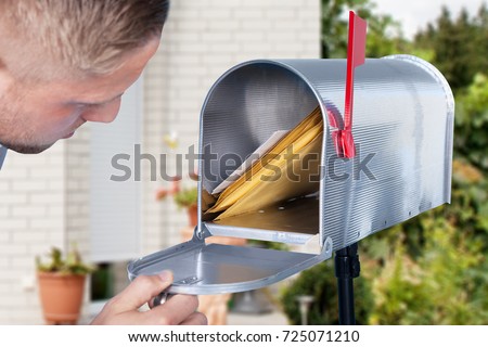 Close-up Of A Man Looking Inside The Silver Mailbox