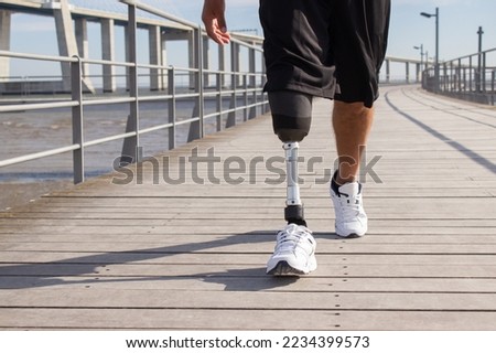 Close-up of man with mechanical leg walking on summer day. Sportsman in black shorts and white sneakers photographed during training. Disability, leisure concept 商業照片 © 