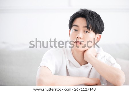 Close-up of a man with a pensive expression, propping his chin on his hand,looking at camera