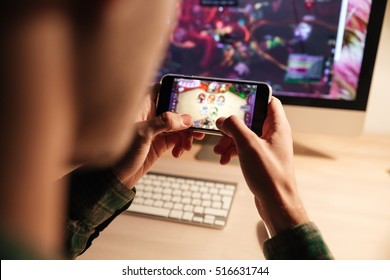 Gros plan sur un homme jouant à un jeu vidéo sur un smartphone le soir à la maison : photo de stock