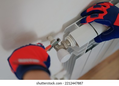 Close-up Of Man Plumber Installing Heating Radiator In Apartment Or House. Builder Installs Hot Water Central Heating System. Repair Concept