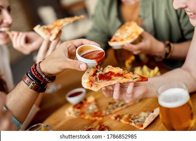 Close-up Of Man Pouring Ketchup On Friend's Slice Of Pizza. 