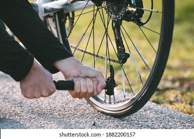 Close-up of a man pumping bicycle wheel on the street. Man inflates bicycle wheel using a pump. Pumping air into an empty wheel of bike - Powered by Shutterstock