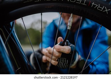 Close-up of a man pumping bicycle wheel in nature.